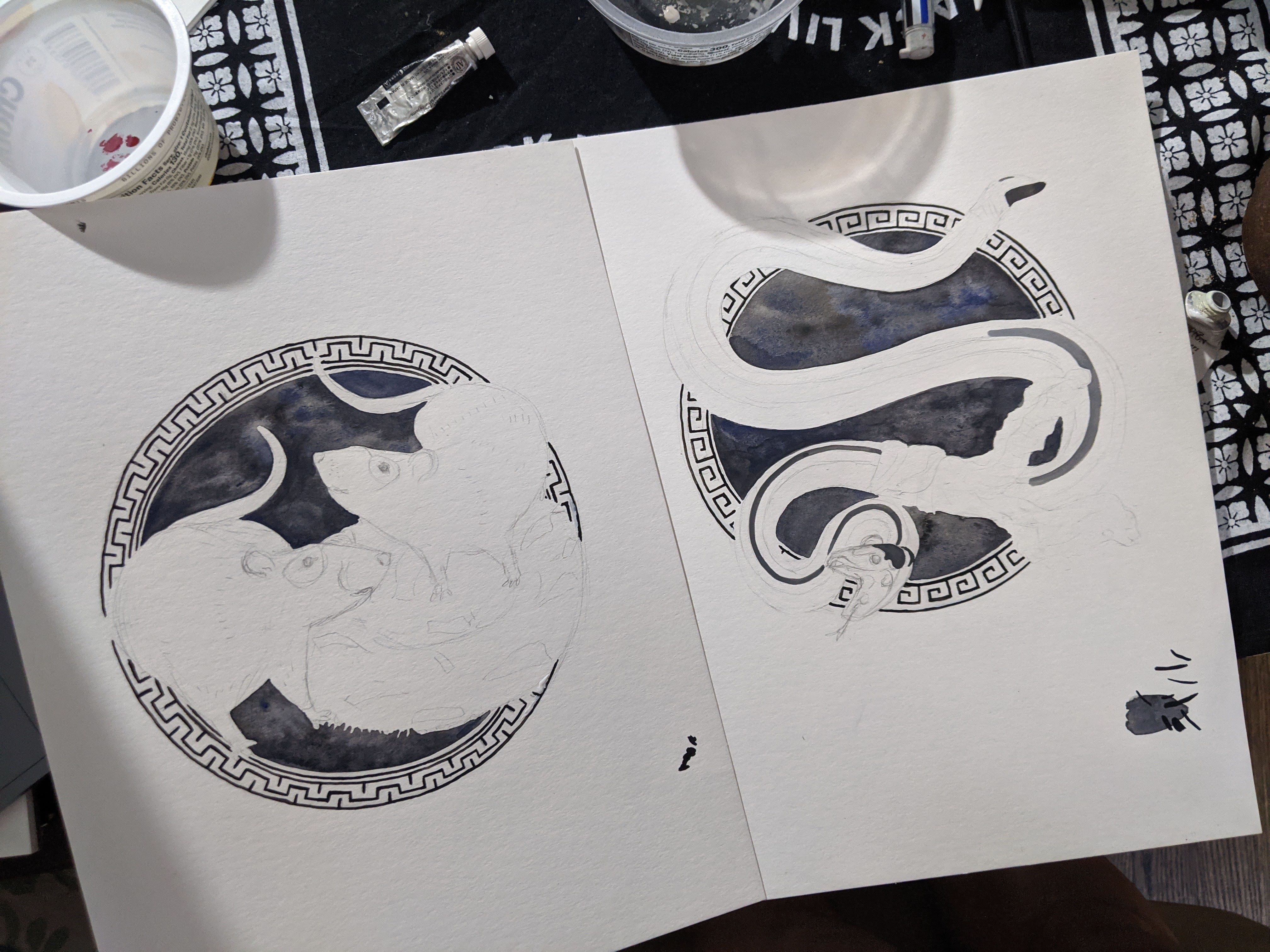 Picture of two partially completed watercolor paintings, one of rats, the other of the snake. they are in circle frames