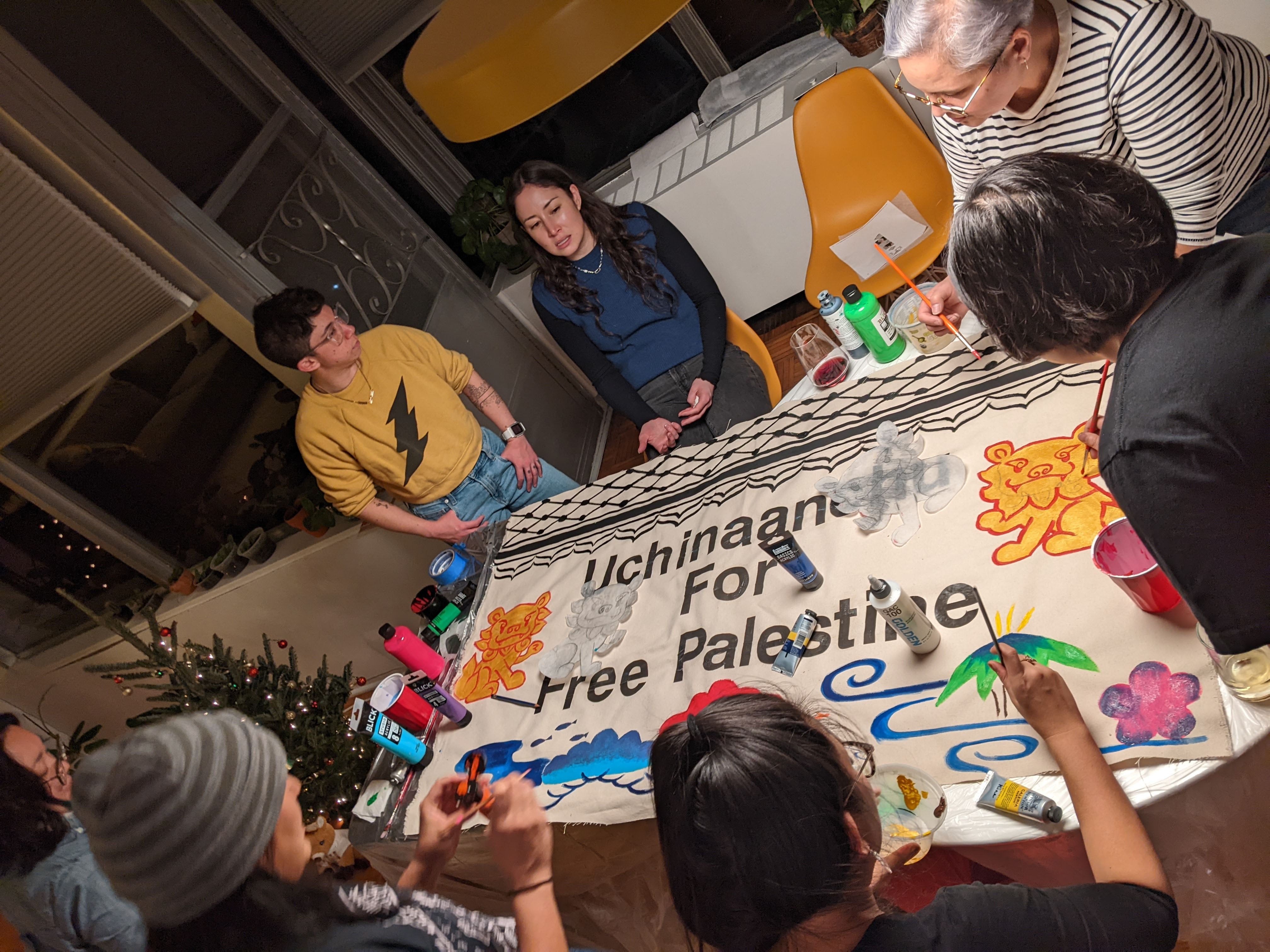 photo of several diasporic uchinanchu people painting a banner in support of palestine