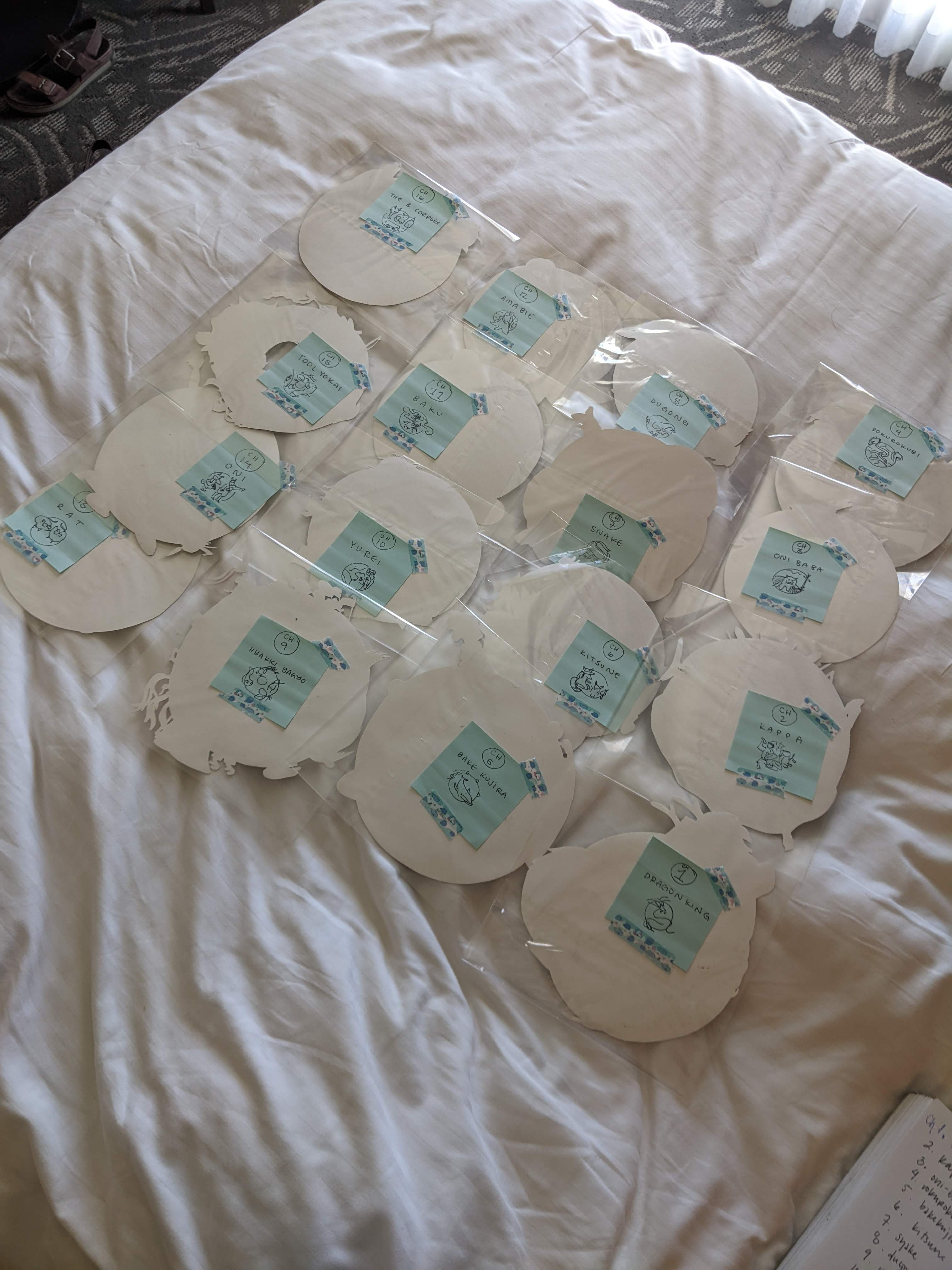 picture of 16 circular paintings wrapped in plastic, lying on a white bed